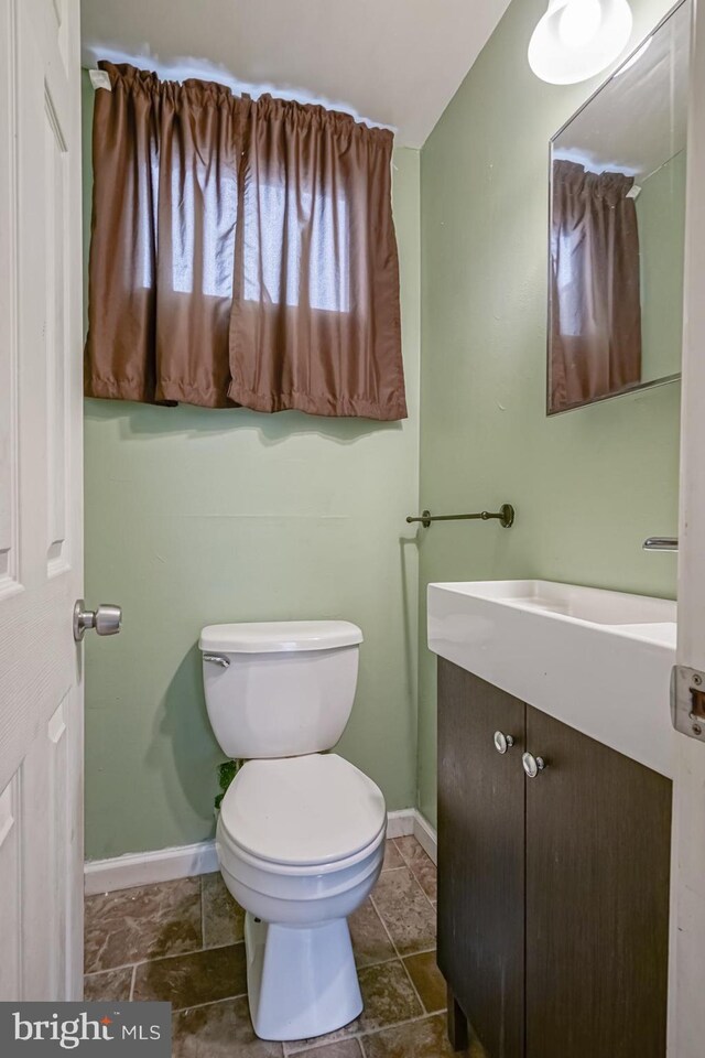 bathroom with baseboards, toilet, and vanity