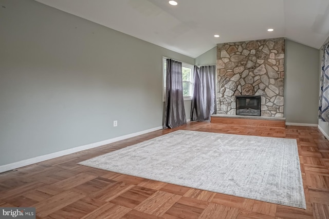 living area with lofted ceiling, a stone fireplace, baseboards, and recessed lighting