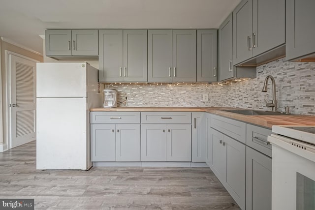 kitchen featuring white appliances, a sink, ornamental molding, wooden counters, and tasteful backsplash