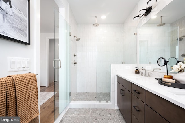 bathroom featuring double vanity, a sink, and a shower stall