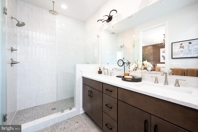 bathroom featuring double vanity, a shower stall, ensuite bathroom, and a sink