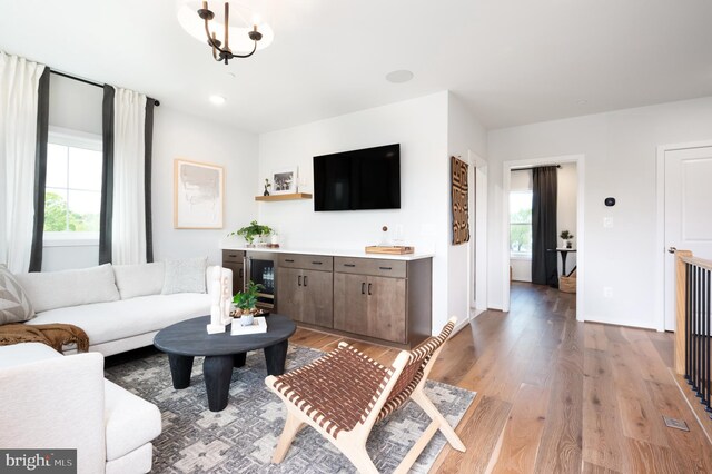 living room with beverage cooler, a healthy amount of sunlight, and light wood finished floors