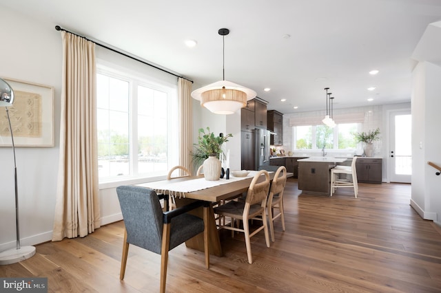 dining space featuring wood finished floors, recessed lighting, and baseboards
