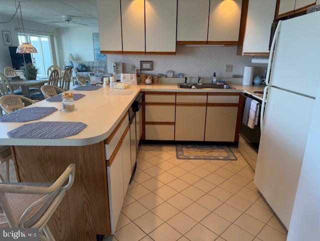 423 14th St Unit 205K, Ocean City, MD 21842 - kitchen featuring freestanding refrigerator, light tile patterned flooring, a sink, a peninsula, and light countertops