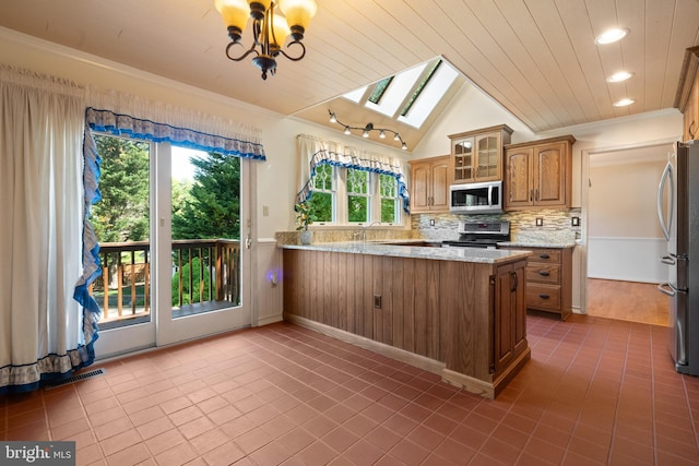 kitchen featuring tile patterned flooring, a peninsula, brown cabinets, backsplash, and stainless steel appliances