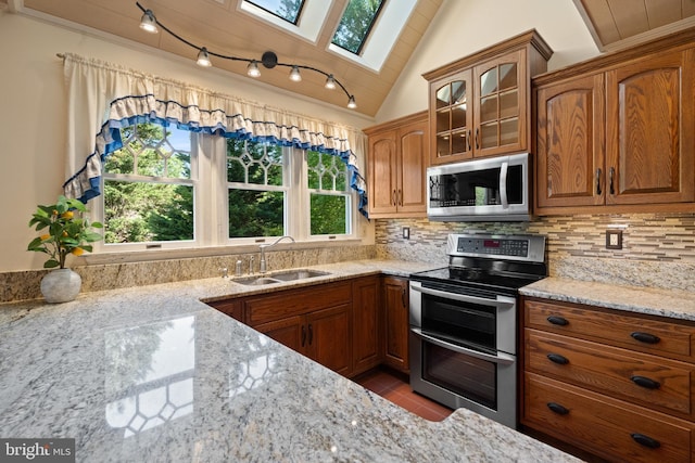 kitchen with a sink, appliances with stainless steel finishes, brown cabinetry, and backsplash