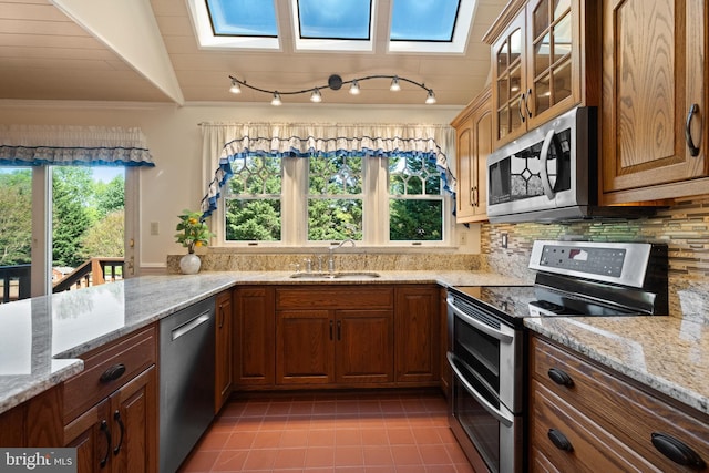 kitchen with decorative backsplash, ornamental molding, glass insert cabinets, a sink, and stainless steel appliances