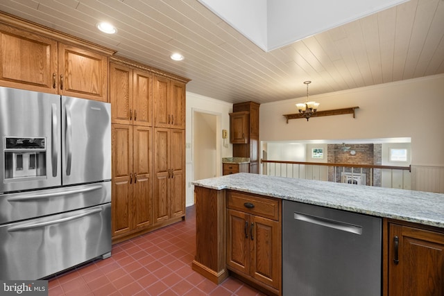 kitchen with crown molding, appliances with stainless steel finishes, brown cabinets, light stone counters, and an inviting chandelier