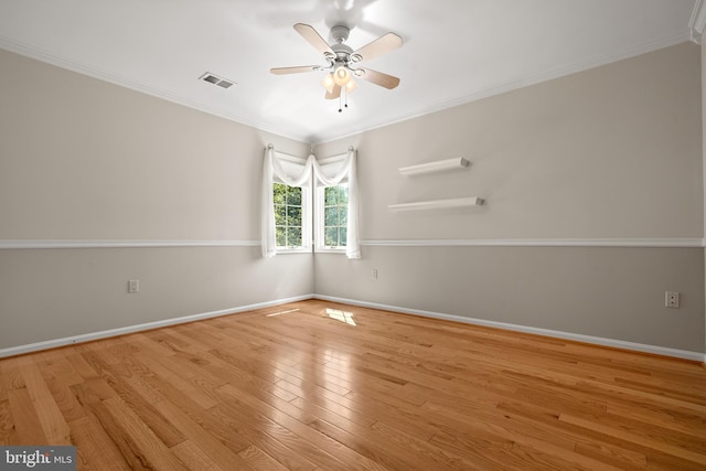 unfurnished room featuring a ceiling fan, baseboards, wood finished floors, visible vents, and ornamental molding