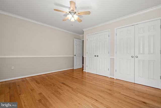 unfurnished bedroom with baseboards, multiple closets, ornamental molding, and light wood-style flooring