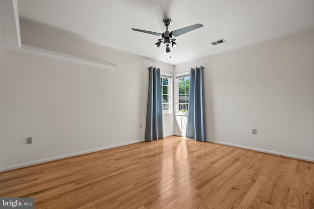 spare room featuring ceiling fan, visible vents, ornamental molding, and light wood-style flooring