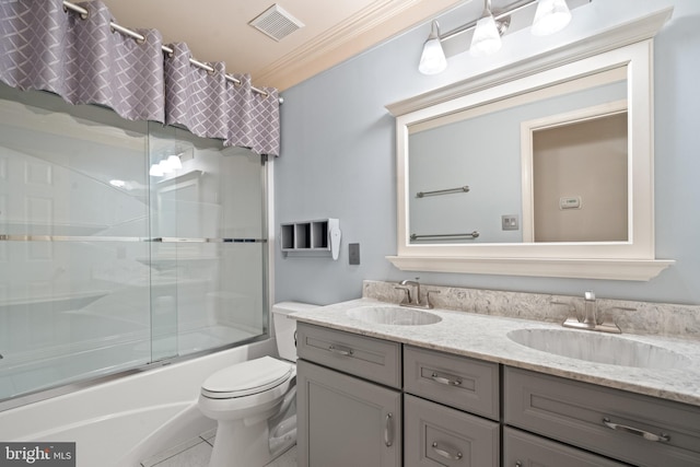bathroom featuring double vanity, a sink, crown molding, and toilet