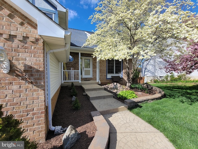 entrance to property featuring brick siding and a shingled roof