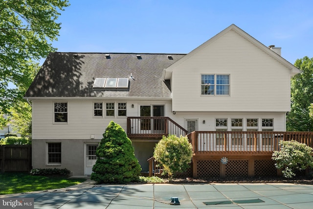 back of house featuring fence, a chimney, and a deck
