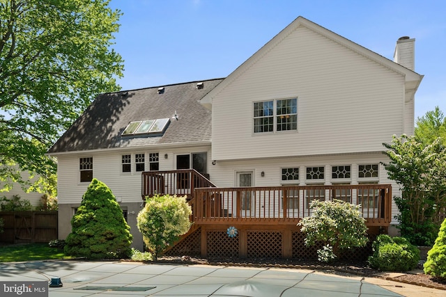 rear view of property featuring a wooden deck, a chimney, and fence