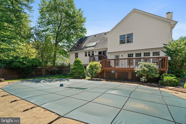 rear view of house featuring a fenced in pool, a chimney, a deck, and fence