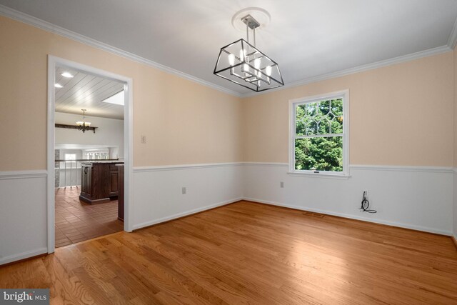 unfurnished dining area with an inviting chandelier, baseboards, crown molding, and wood finished floors