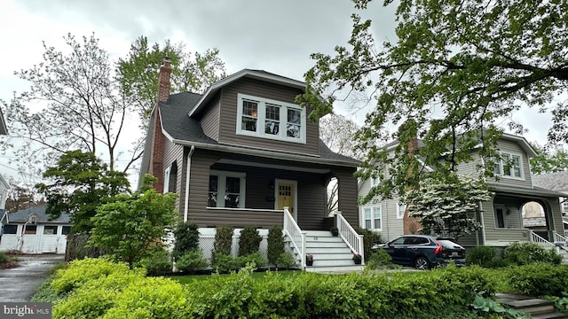 view of front of property featuring covered porch, stairway, a chimney, and a shingled roof