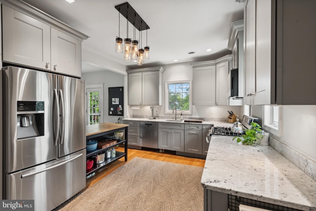 kitchen with appliances with stainless steel finishes, gray cabinets, light wood finished floors, recessed lighting, and hanging light fixtures