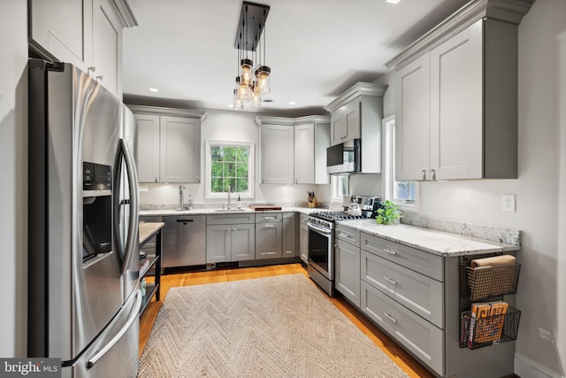 kitchen with appliances with stainless steel finishes, gray cabinetry, light wood finished floors, and recessed lighting
