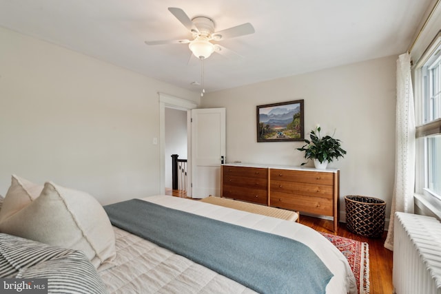 bedroom with radiator, wood finished floors, and a ceiling fan