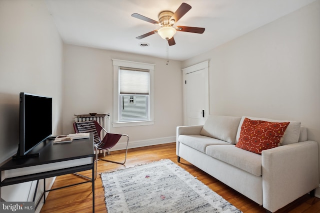 living area with ceiling fan, baseboards, and wood finished floors