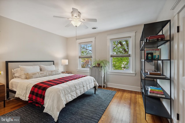 bedroom with radiator, wood-type flooring, baseboards, and ceiling fan
