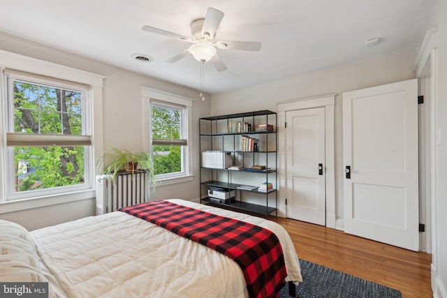 bedroom featuring wood finished floors, radiator, and ceiling fan