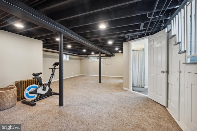 below grade area with radiator heating unit, carpet floors, stairs, and baseboards