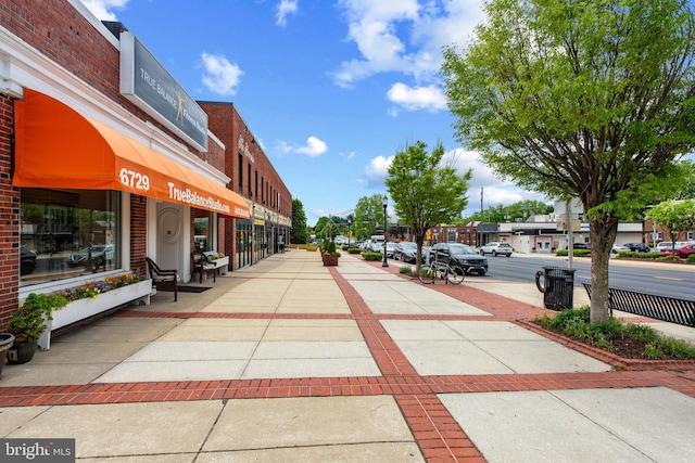 view of asphalt road featuring sidewalks and street lighting