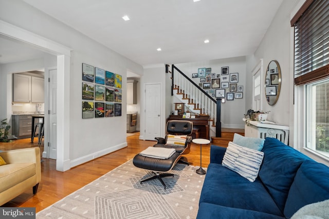 living area with light wood-type flooring, stairway, baseboards, and recessed lighting