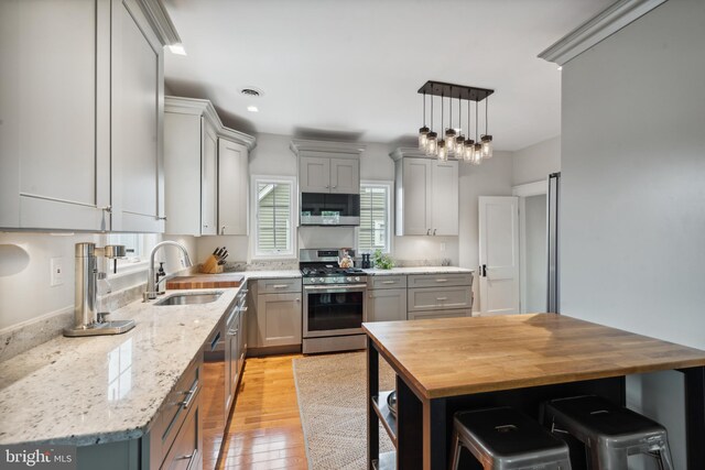 kitchen featuring stainless steel range with gas stovetop, dishwasher, butcher block counters, gray cabinets, and light wood-type flooring