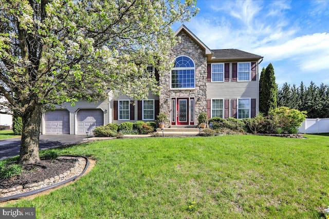 view of front of property featuring fence, driveway, a front yard, and stone siding