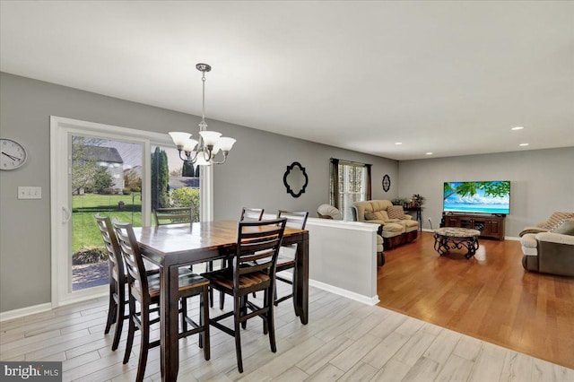 dining space featuring baseboards, light wood-type flooring, an inviting chandelier, and recessed lighting