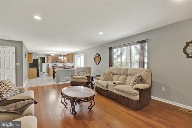 living room featuring baseboards, visible vents, light wood-style flooring, and recessed lighting