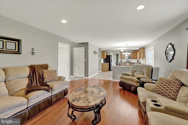 living area featuring recessed lighting, an inviting chandelier, baseboards, and light wood-style floors