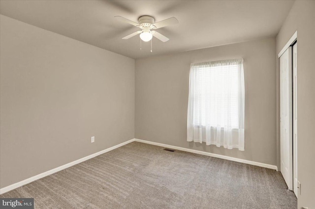 empty room with carpet, visible vents, ceiling fan, and baseboards