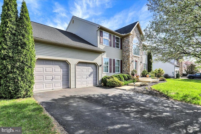 view of front of home with a front lawn, stone siding, a garage, and aphalt driveway