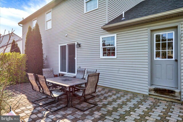 exterior space with outdoor dining area, a shingled roof, and a patio area