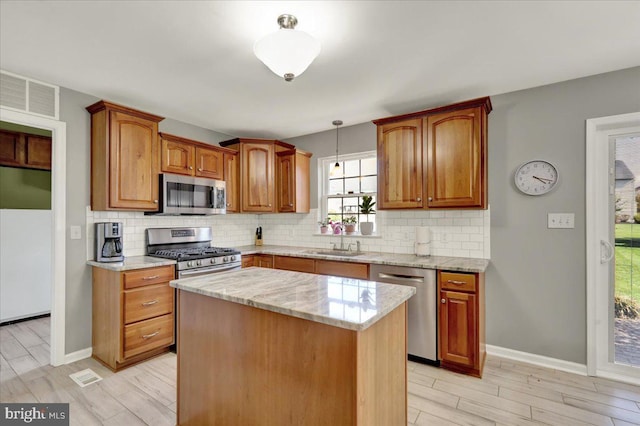 kitchen featuring light stone countertops, backsplash, appliances with stainless steel finishes, and a sink
