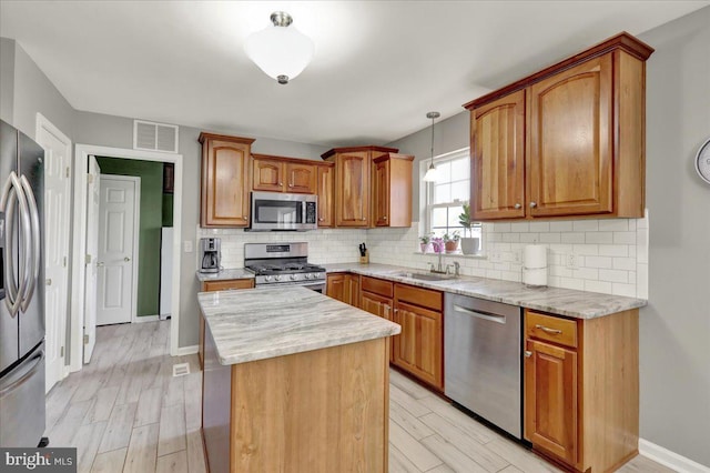 kitchen featuring a sink, appliances with stainless steel finishes, visible vents, a kitchen island, and light wood finished floors
