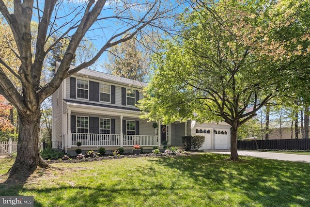 traditional home with a porch, a front lawn, driveway, and fence