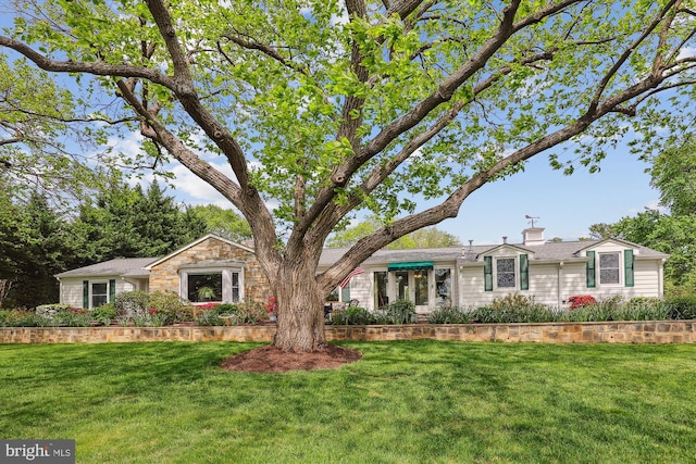 ranch-style house with a chimney and a front yard