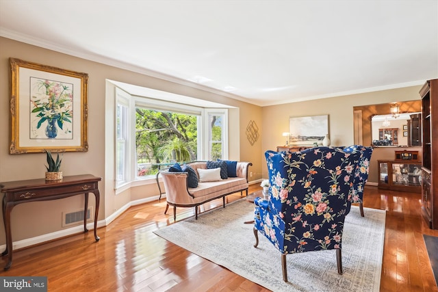 living room featuring visible vents, ornamental molding, wood-type flooring, and baseboards