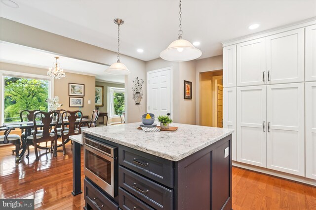 kitchen with recessed lighting, a center island, white cabinetry, stainless steel microwave, and hanging light fixtures