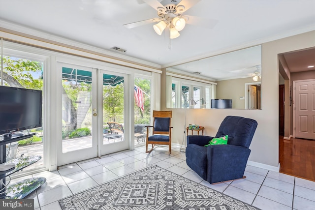 living area with crown molding, a ceiling fan, light tile patterned flooring, and visible vents
