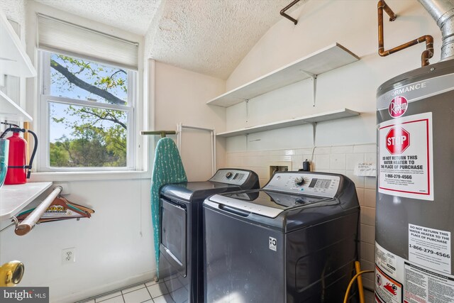 washroom with gas water heater, laundry area, a textured ceiling, tile patterned flooring, and separate washer and dryer