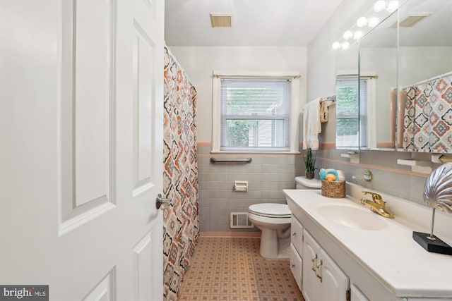 bathroom with tile walls, visible vents, a wainscoted wall, and vanity