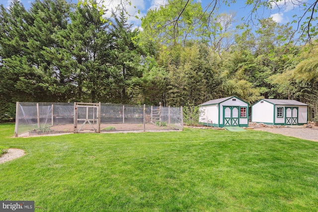 view of yard with fence, a storage unit, an outdoor structure, and a vegetable garden