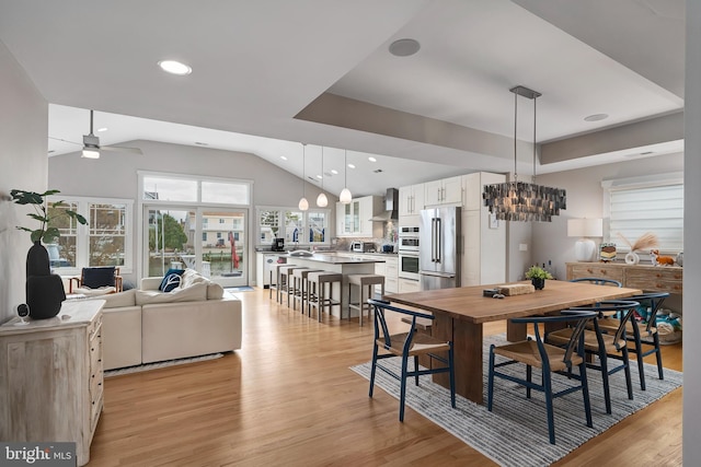 dining area with vaulted ceiling, light wood-type flooring, a ceiling fan, a chandelier, and recessed lighting